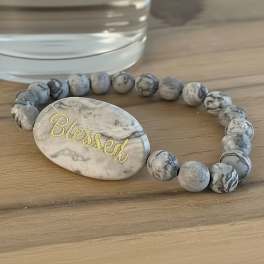 Bracelet with marbled beads and 'Blessed' charm on a wooden surface